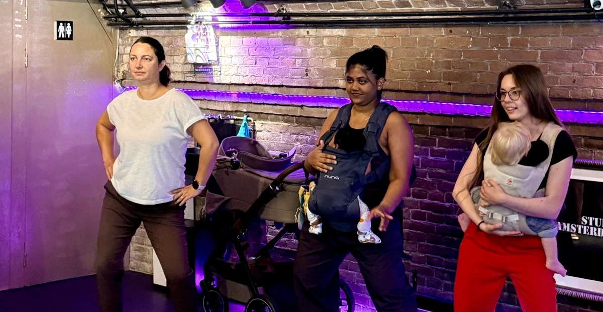 Moms dancing together while wearing their babies in carriers at the Mama Circle babywearing dance gathering