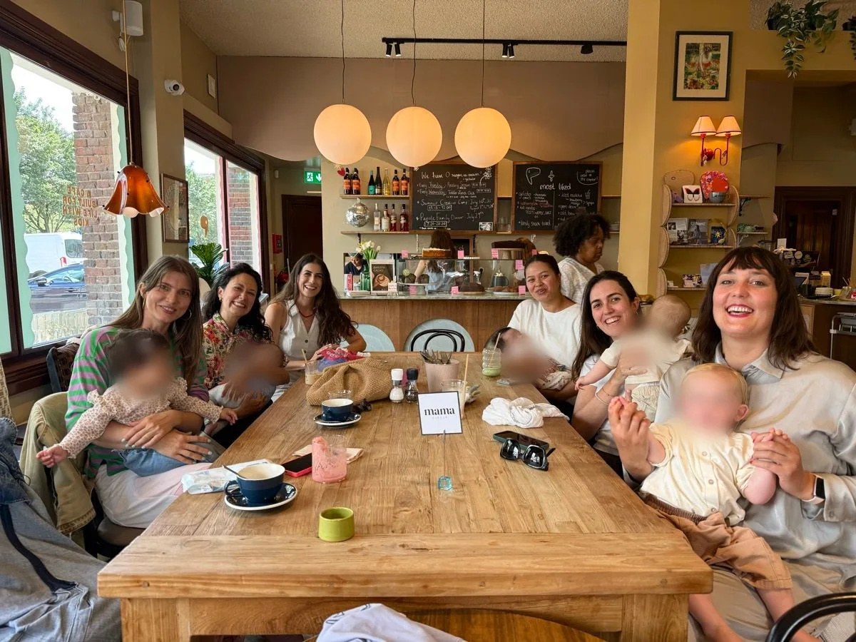 Moms and their babies gathered around a cafe table at a Mama Circle meetup