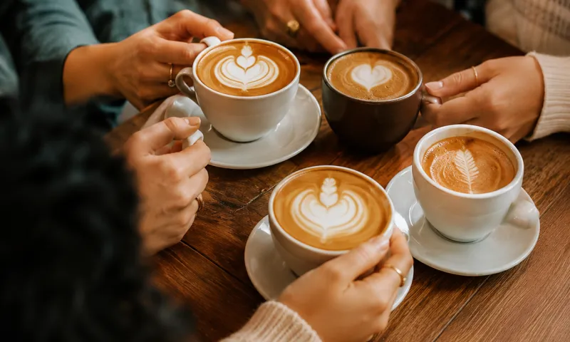 Four cups of coffee shared around a café table