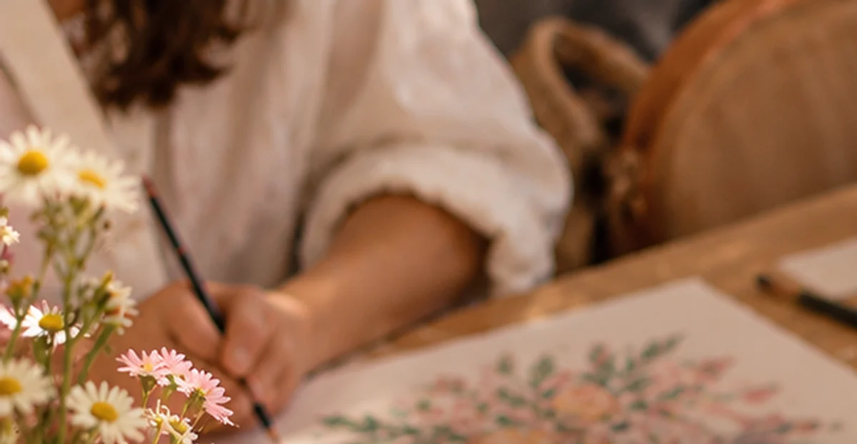 A mom drawing flowers at a table with artwork and fresh flowers for the Creative Circle drawing event