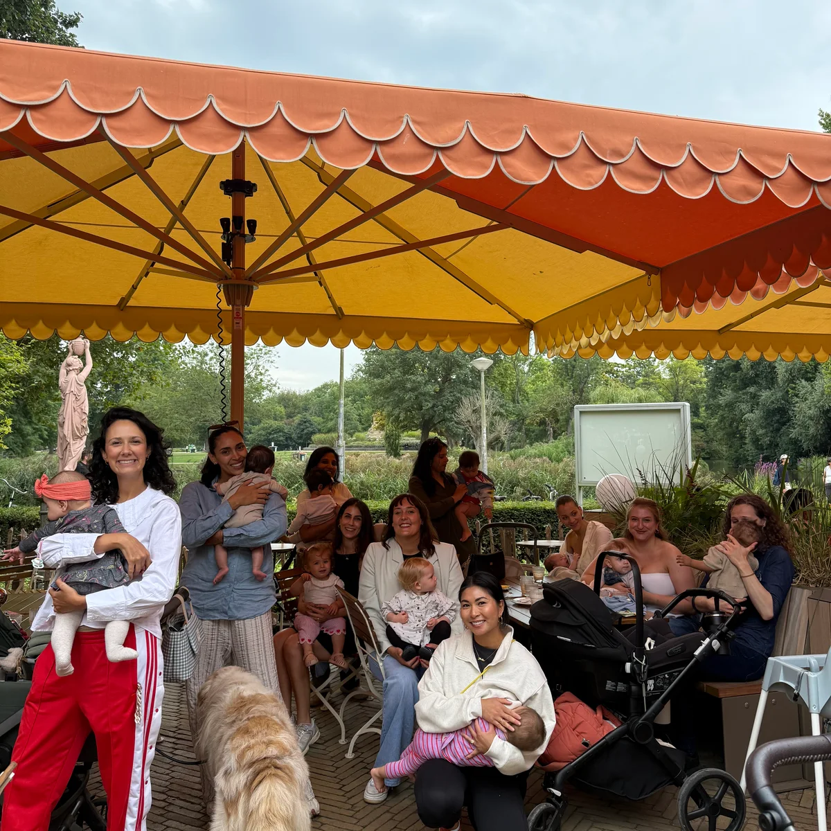 Moms and little ones gathered together beneath a red and yellow canopy