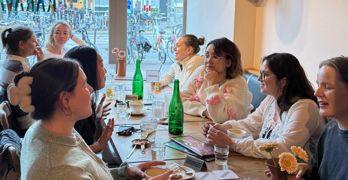 A group of moms sharing conversation around a café table in Amsterdam